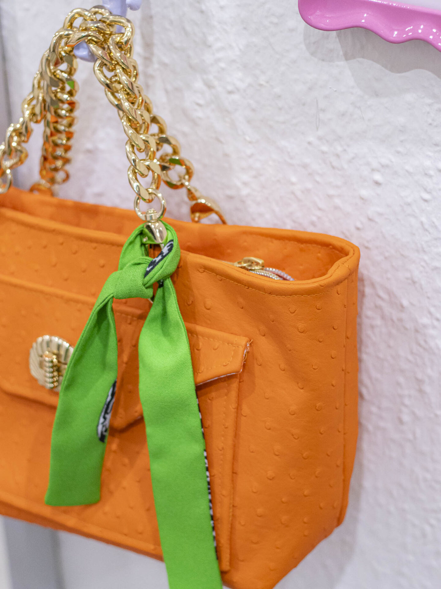 Locker um den Henkel einer orangen Tasche gebundener Skinny Scarf