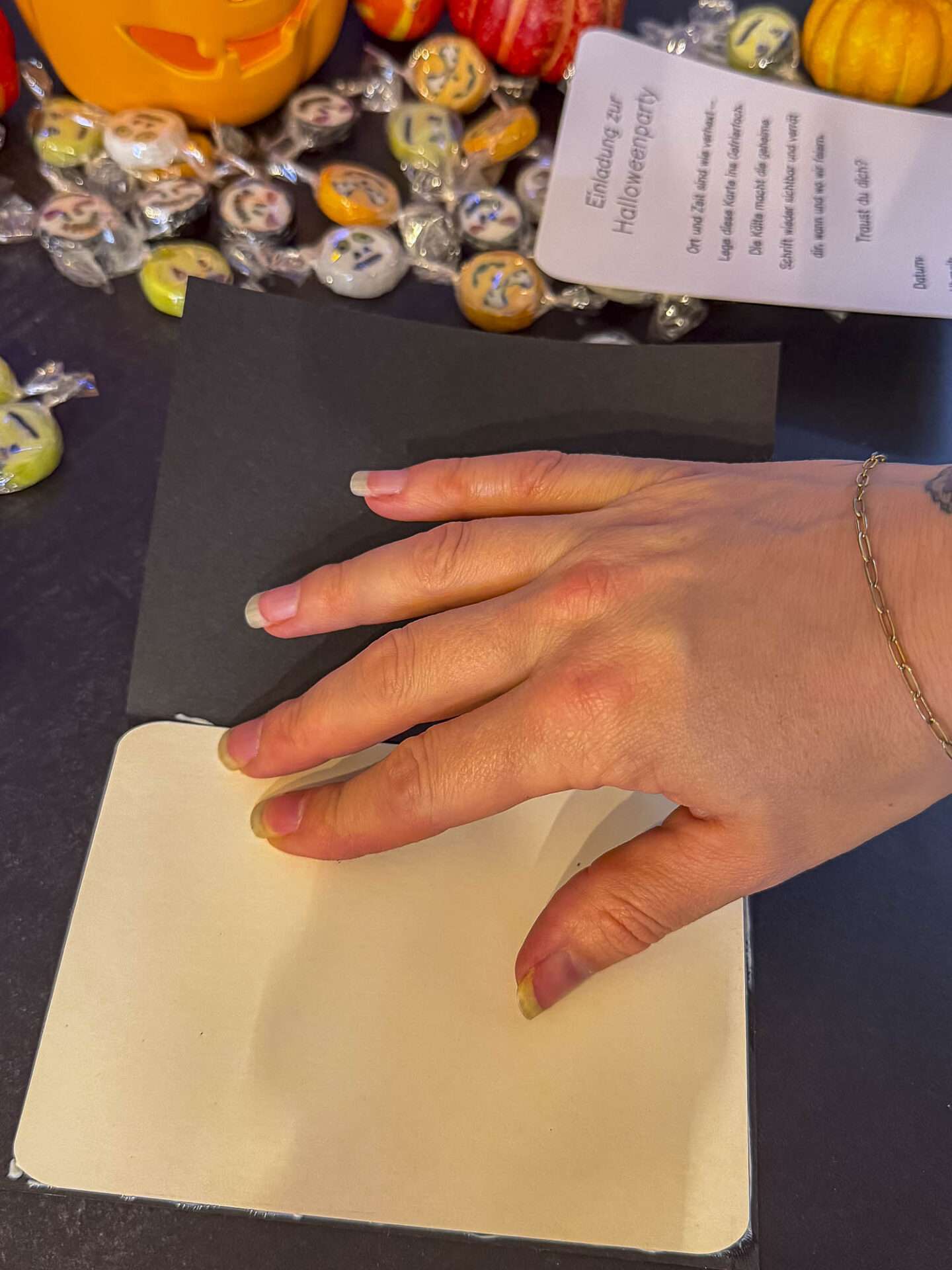 Den farbigen Hintergrund hinter das ausgeschnittene Halloweenmotiv kleben und mit der Hand festdrücken.
